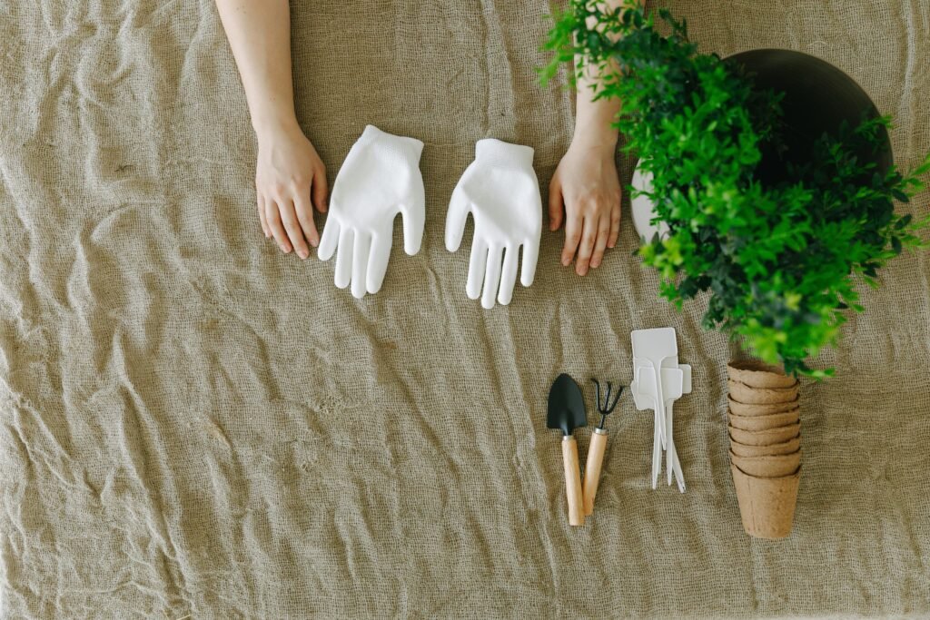 Top view of gardening tools with white gloves and hands ready to plant.
