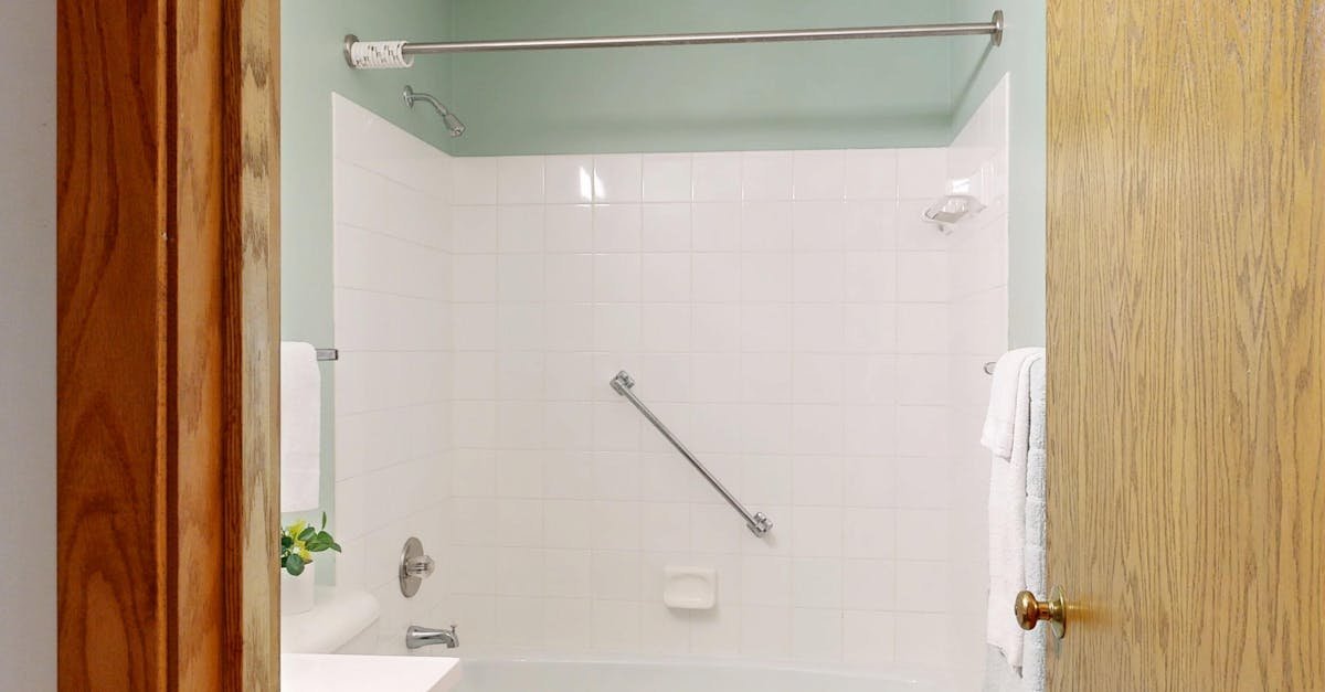 Clean and modern bathroom featuring white ceramic tiles and a bathtub.