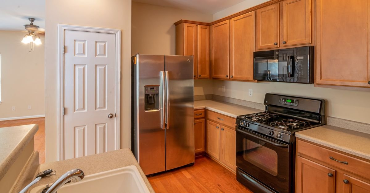 Contemporary kitchen featuring wooden cabinets, stainless steel refrigerator, and modern appliances.